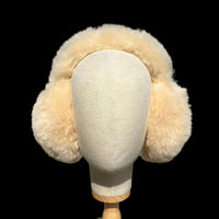 A cream fur earmuff displayed on a cream fabric mannequin head.