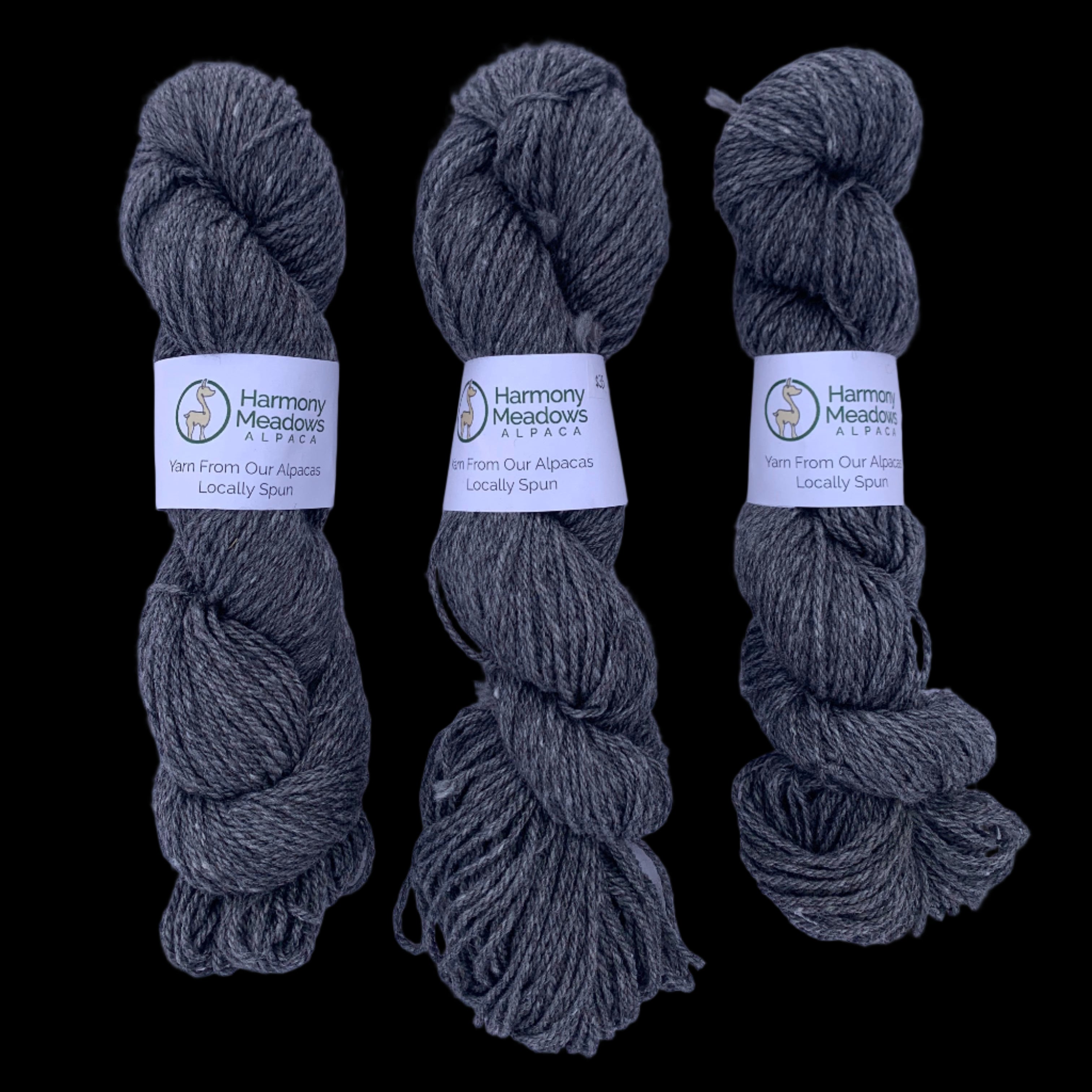 Three skeins of gray yarn with labels on a light gray background