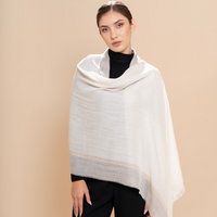 Woman wearing a white shawl over a black outfit on a beige background