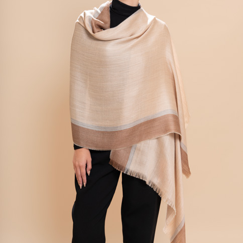 Woman wearing a beige shawl against a beige background
