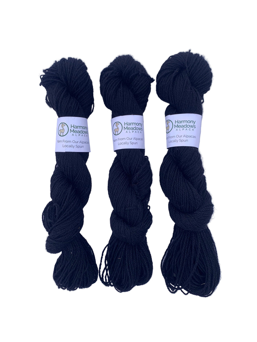 Three skeins of black yarn with labels on a white background